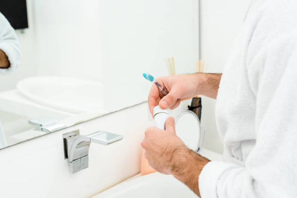 浴室で歯磨き粉と歯ブラシを持って男性の手のビューをトリミング - 写真・画像