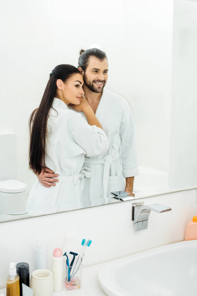 tender couple  in white bathrobes hugging in bathroom at morning  - Foto, immagini