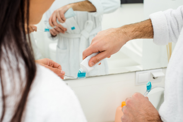 cropped view of man adding toothpaste on woman toothbrush - Photo, image