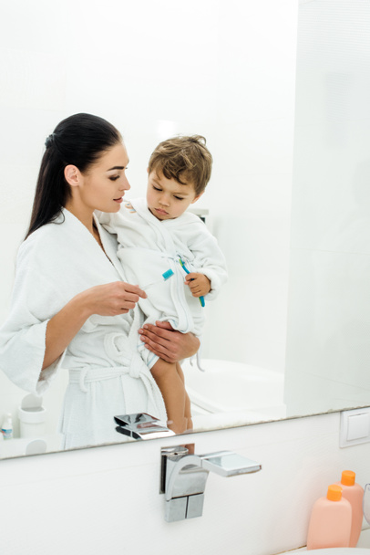 madre e hijo en batas blancas cepillándose los dientes juntos
 - Foto, Imagen