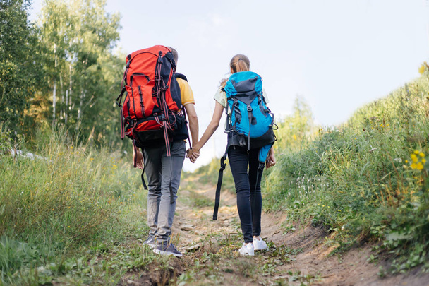couple of tourists with backpacks hiking in a forest - Foto, Imagem