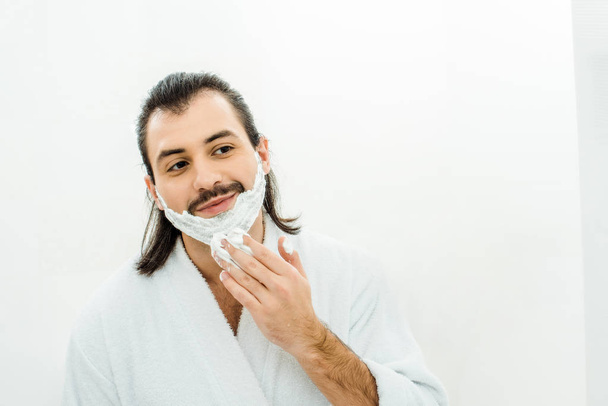 Adult man applying shaving foam in bathroom - Фото, изображение
