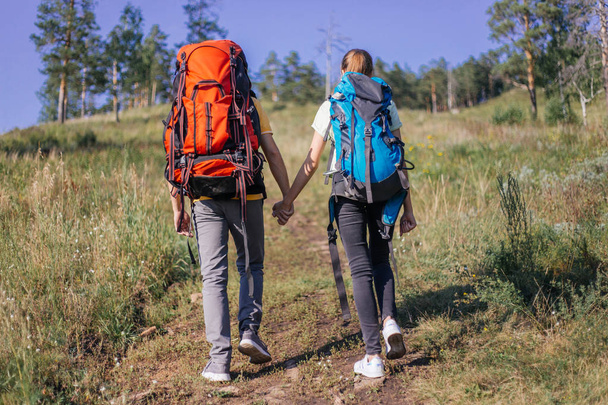 couple of tourists with backpacks hiking in a forest - Fotó, kép