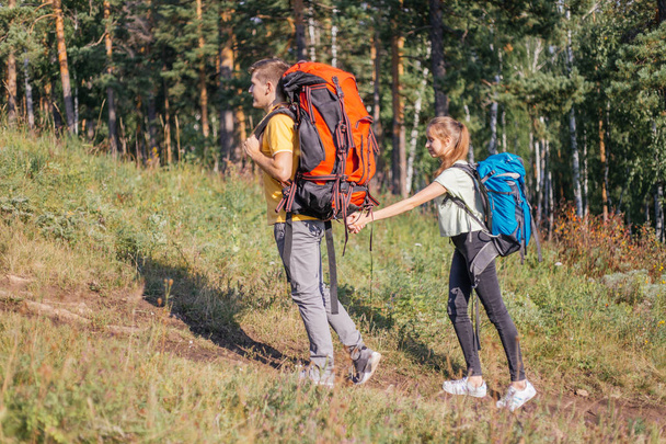 couple of tourists with backpacks hiking in a forest - Фото, изображение