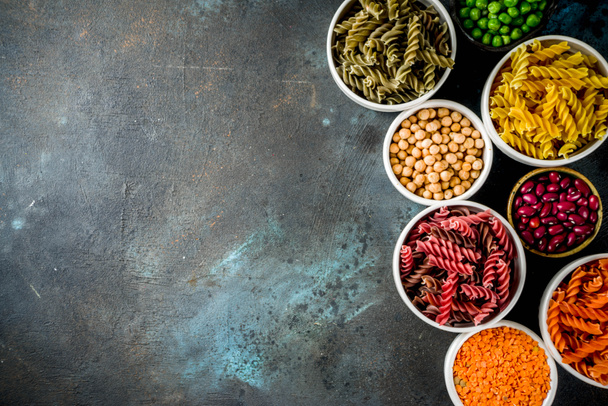 Trend healthy food, vegan diet concept. Multi colored legume pasta with raw beans. Beans, chickpeas, green peas, lentils. Copy space top view - Fotó, kép