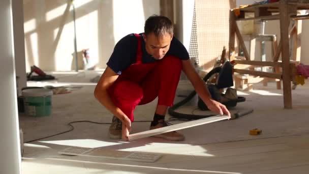 Young man installing ceramic floor tiles - Кадры, видео