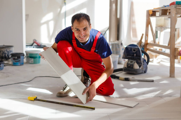 Nuori mies asentamassa keraamiset lattialaatat
 - Valokuva, kuva