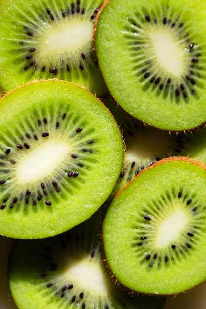 Sliced green fresh kiwi fruit pieces lying on table, flat lay view, healthy diet - Foto, imagen