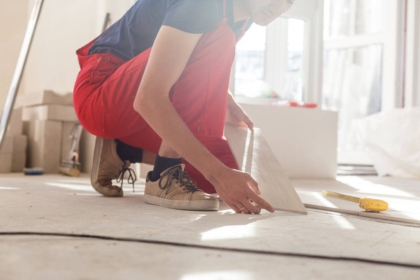 Молодий чоловік встановлює керамічну плитку підлоги
 - Фото, зображення
