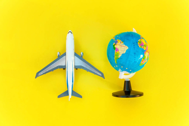 Flat Lay with plane and globe on yellow colourful trendy modern fashion background. Vacation travel summer weekend sea adventure trip concept - 写真・画像