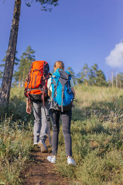 couple of tourists with backpacks hiking up a mountain - Фото, изображение