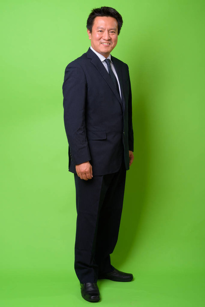 Mature Japanese businessman against green background - Foto, afbeelding