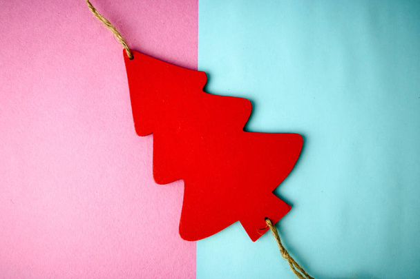 Festive New Year's Christmas beautiful bright multi-colored joyful blue and pink background with a small toy wooden red and white cute Christmas tree. Flat lay. Top view. Holiday decorations - Photo, Image