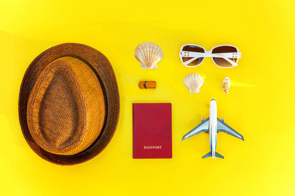 Flat Lay con sombrero, avión, pasaporte, gafas de sol y concha sobre fondo de moda moderna de color amarillo. Vacaciones verano fin de semana mar aventura viaje concepto
 - Foto, Imagen