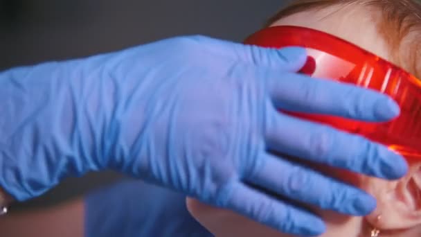 Οδοντιατρική, ιατρική. Οδοντίατρος βάζει προστατευτικά γυαλιά babys πρόσωπο και σε συνεργασία με τον οδοντιατρικό λάμπα πολυμερισμού - Πλάνα, βίντεο