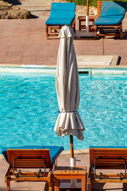 Κοντινό πλάνο του μια πισίνα με ξαπλώστρες και μια ομπρέλα παραλίας - Φωτογραφία, εικόνα