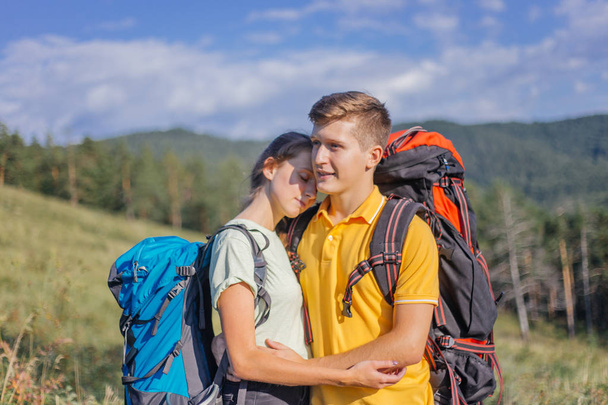 couple of tourists with backpacks hiking up a mountain - 写真・画像