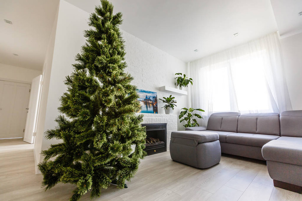 Weihnachtsbaum im gemütlichen Wohnzimmer mit weißem Steinkamin, Konzept der Silvesterausstattung  - Foto, Bild