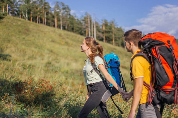 couple of tourists with backpacks hiking up a mountain - Zdjęcie, obraz