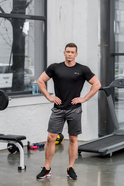 handsome muscular bodybuilder looking at camera in gym - Фото, зображення
