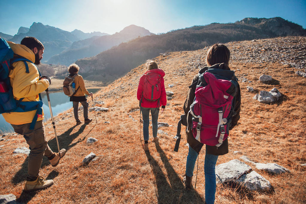Ομάδα πεζοπόρων περπατώντας πάνω σε ένα βουνό τη φθινοπωρινή μέρα κοντά στη λίμνη. - Φωτογραφία, εικόνα