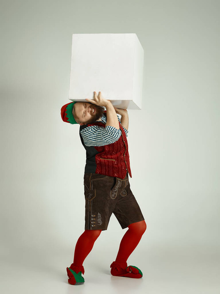friendly man dressed like a funny gnome posing on an isolated gray background - Foto, Bild