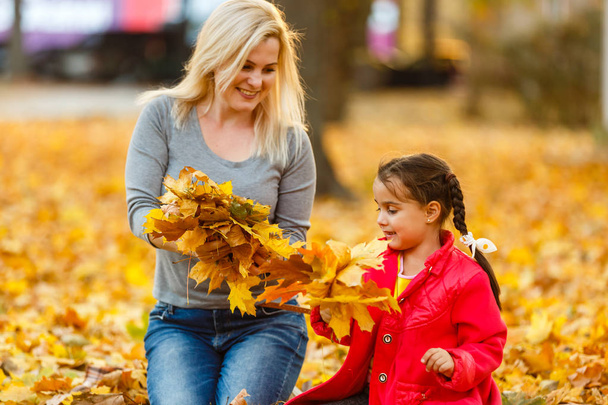 Mother and daughter having fun in autumn yellow park - Foto, afbeelding