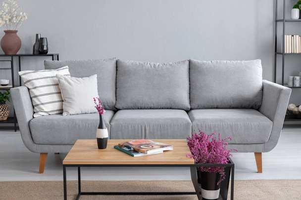 Real photo of a grey sofa, coffee table and lavender flower in a living room interior - Photo, image