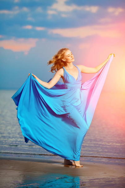 Luxury woman in a long blue evening  dress on the beach. Beautiful young girl at the - Foto, afbeelding
