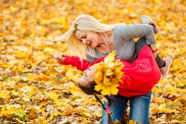 Mother and daughter having fun in autumn yellow park - Fotoğraf, Görsel