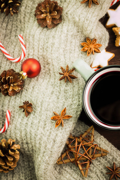 Copa caliente al vapor de Navidad de vino glint con especias, anís, conos de abeto, galletas en forma de estrella, caramelos rojos, pimienta y bufanda gris sobre fondo de madera. Vista desde arriba. Puesta plana
. - Foto, imagen