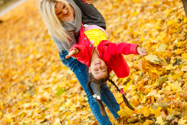 Mother and daughter having fun in autumn yellow park - Fotografie, Obrázek