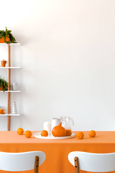Fruits on orange table in white dining room interior with chairs and copy space on the wall. Real photo - Foto, imagen