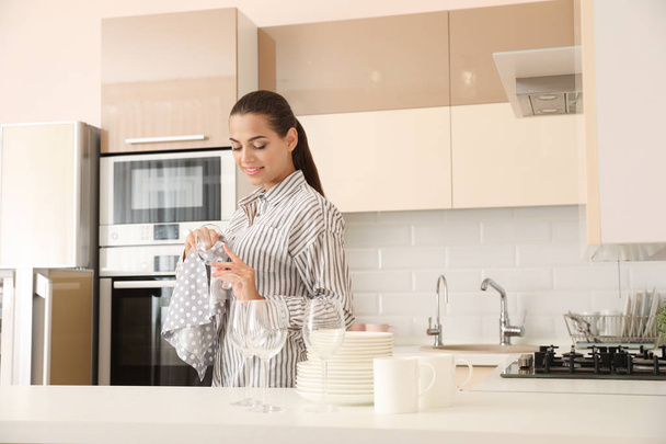 Young woman wiping clean glass in kitchen. Dish washing - Zdjęcie, obraz