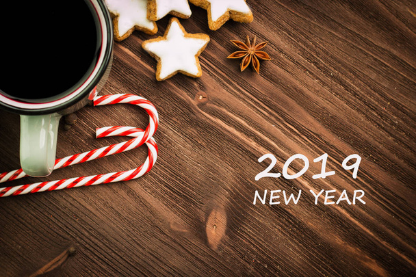 Hete dampende kop glint wijn met specerijen, anijs, cookies in een vorm van sterren, rode snoepjes, peper op houten achtergrond met tekst 2019 Nieuwjaar. Flat lag. Van bovenaf bekijken. - Foto, afbeelding