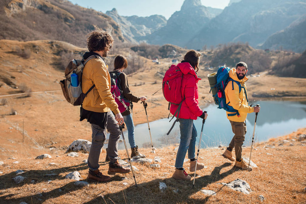 Группа туристов, прогуливающихся по горе осенним днем у озера
. - Фото, изображение