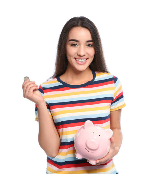 Portrait of young woman with piggy bank and coin on white background - Фото, изображение