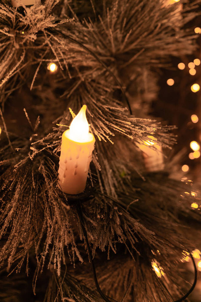 Traditional candles on flocked Christmas tree with glowing lights background - Zdjęcie, obraz