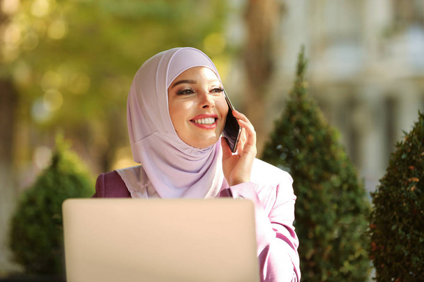 Muslim woman talking on phone in outdoor cafe - Foto, Imagem