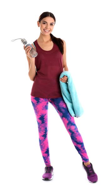 Beautiful young woman in sportswear with towel and bottle of water on white background - Foto, imagen
