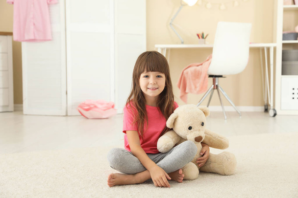 Cute little girl playing with teddy bear at home - 写真・画像
