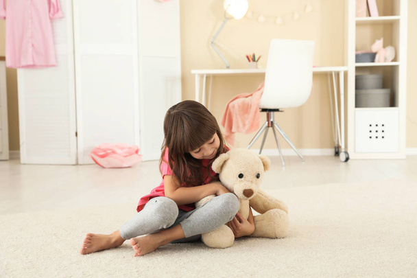Cute little girl playing with teddy bear at home - Fotó, kép