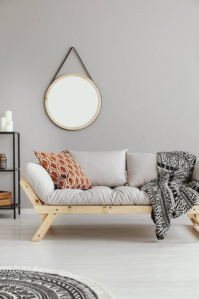 Mockup of round mirror above grey settee with patterned blanket in boho flat interior. Real photo - Foto, Imagem