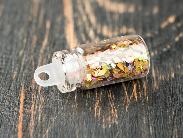 Brokat w małej butelce dla paznokci na podłoże drewniane - Zdjęcie, obraz
