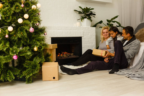 Rodina s přítomné sedící na podlaze vánoční stromeček v obýváku  - Fotografie, Obrázek