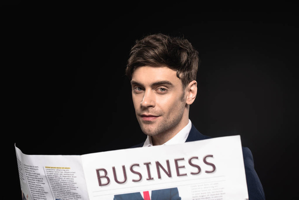 close-up portrait of handsome young businessman with newspaper looking at camera isolated on black - Fotoğraf, Görsel