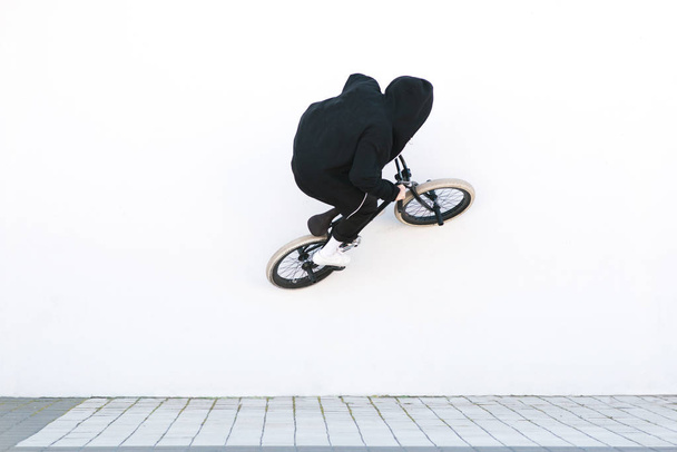 BMX rider rides a bicycle on the white wall. Young man is doing tricks on BMX. BMX freestyle - Photo, Image