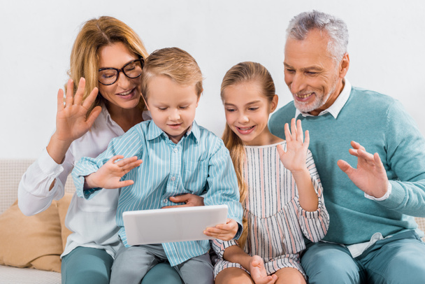 祖父母と孫の自宅をデジタル タブレットでビデオ通話しながら手を振って - 写真・画像