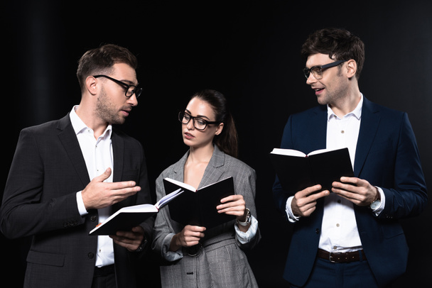 group of serious business people working with notebooks together isolated on black - Фото, изображение