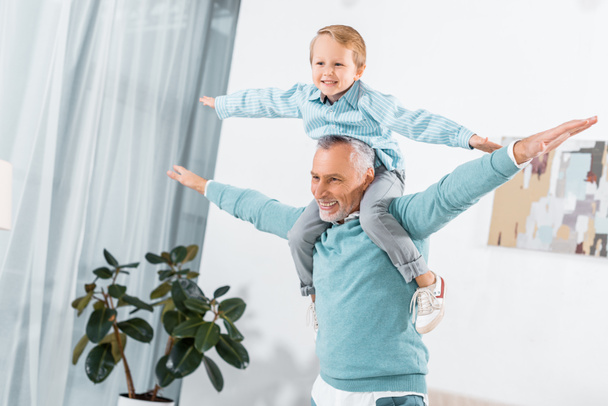 ridere bambino seduto sulle spalle del nonno e divertirsi a casa
 - Foto, immagini